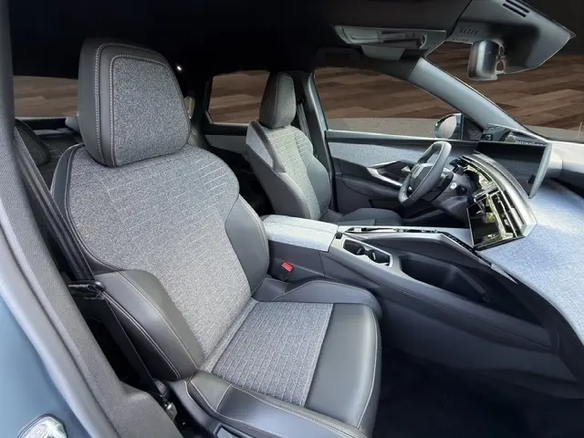 Vue intérieure côté passager avant du Peugeot 3008 Hybrid 2026, sièges tissu et cuir, tableau de bord avec écran tactile panoramique.