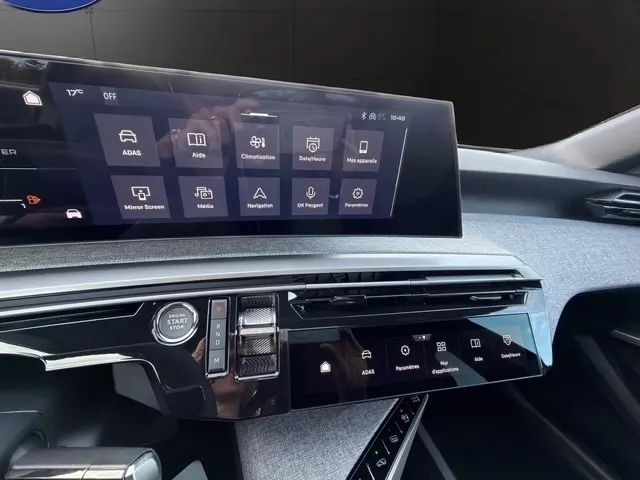 Vue rapprochée du tableau de bord tactile du Peugeot 3008 hybride 2026, avec écran multifonctions et bouton démarrage.