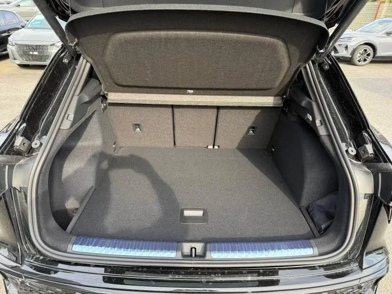Coffre ouvert vu de l'arrière d'un Audi Q3 2.0 TDI noir Mythique métallisé avec intérieur de coffre spacieux et propre.