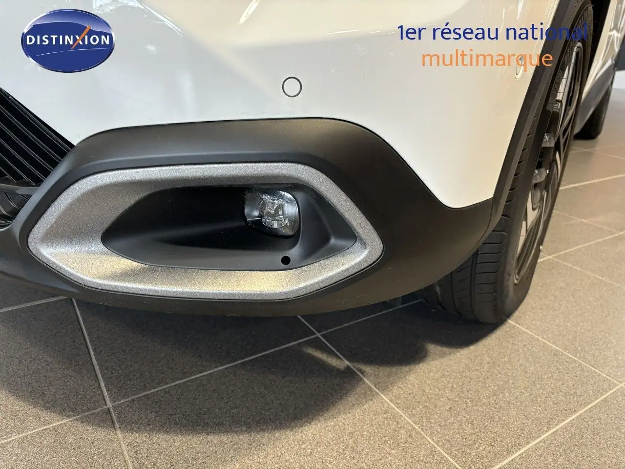 Gros plan sur l'antibrouillard avant droit du Citroën C4 blanc 2022 avec pare-chocs noir et jante visible.