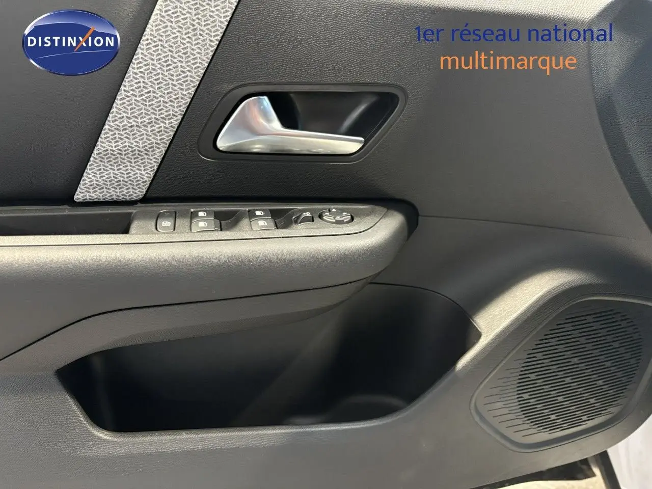 Intérieur de la porte côté gauche d'une Citroën C4 blanche 2022, avec commandes de vitres et poignée argentée.