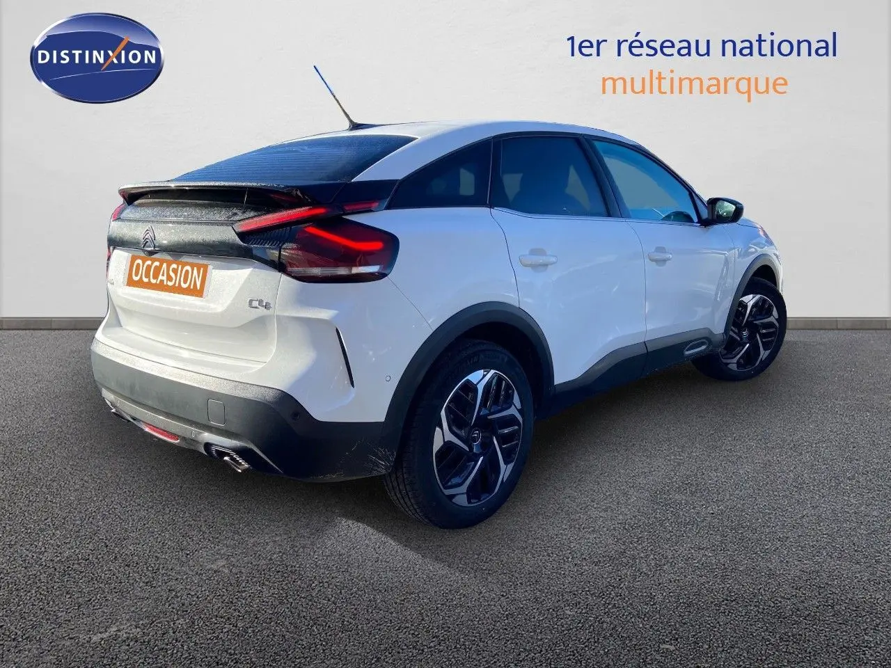 Citroën C4 blanc vue 3/4 arrière droit avec toit noir et jantes alliage bicolores sur sol gris.