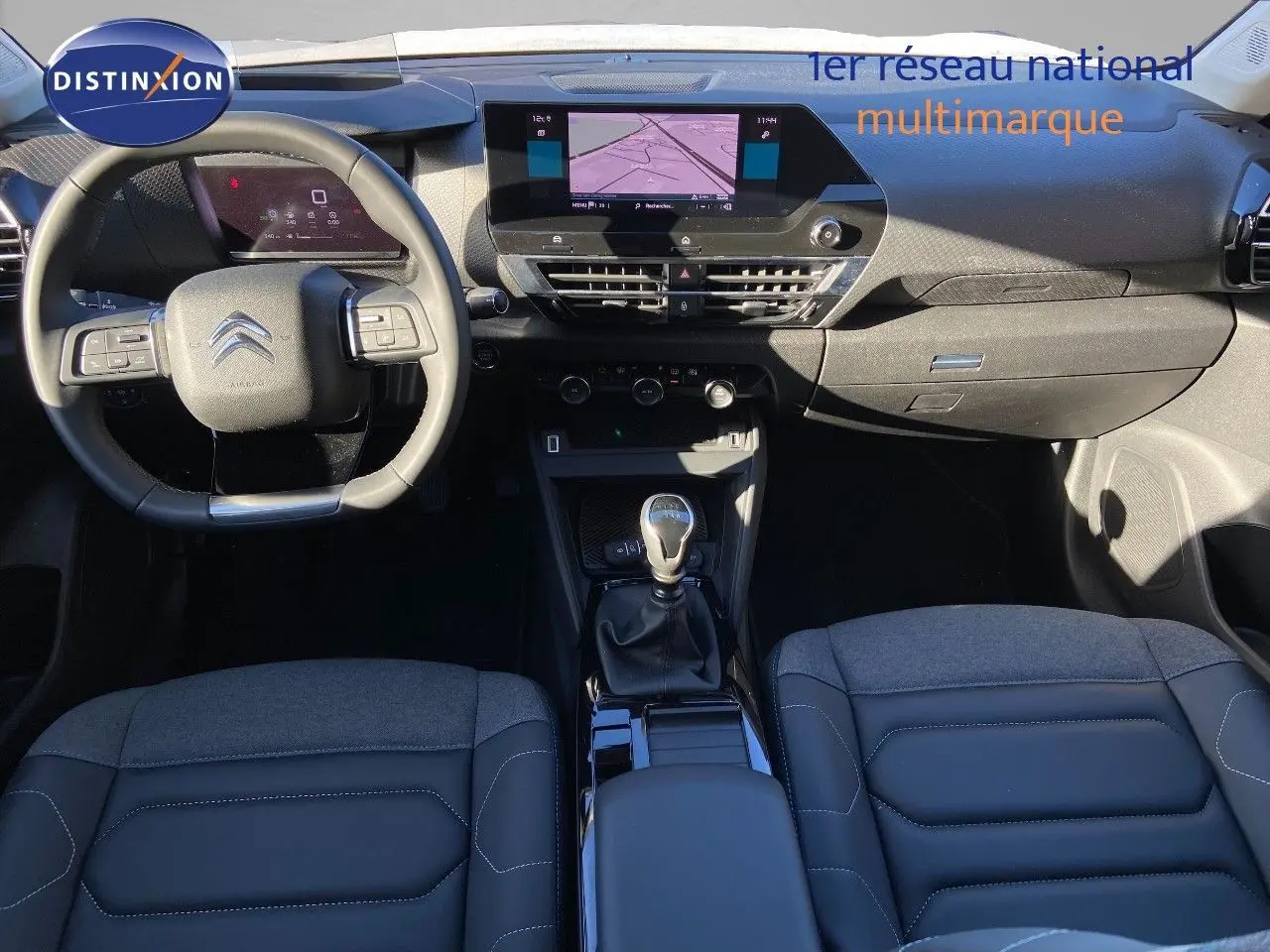 Vue intérieure avant de la Citroën C4 blanche 2022, avec tableau de bord moderne et levier de vitesses manuel.