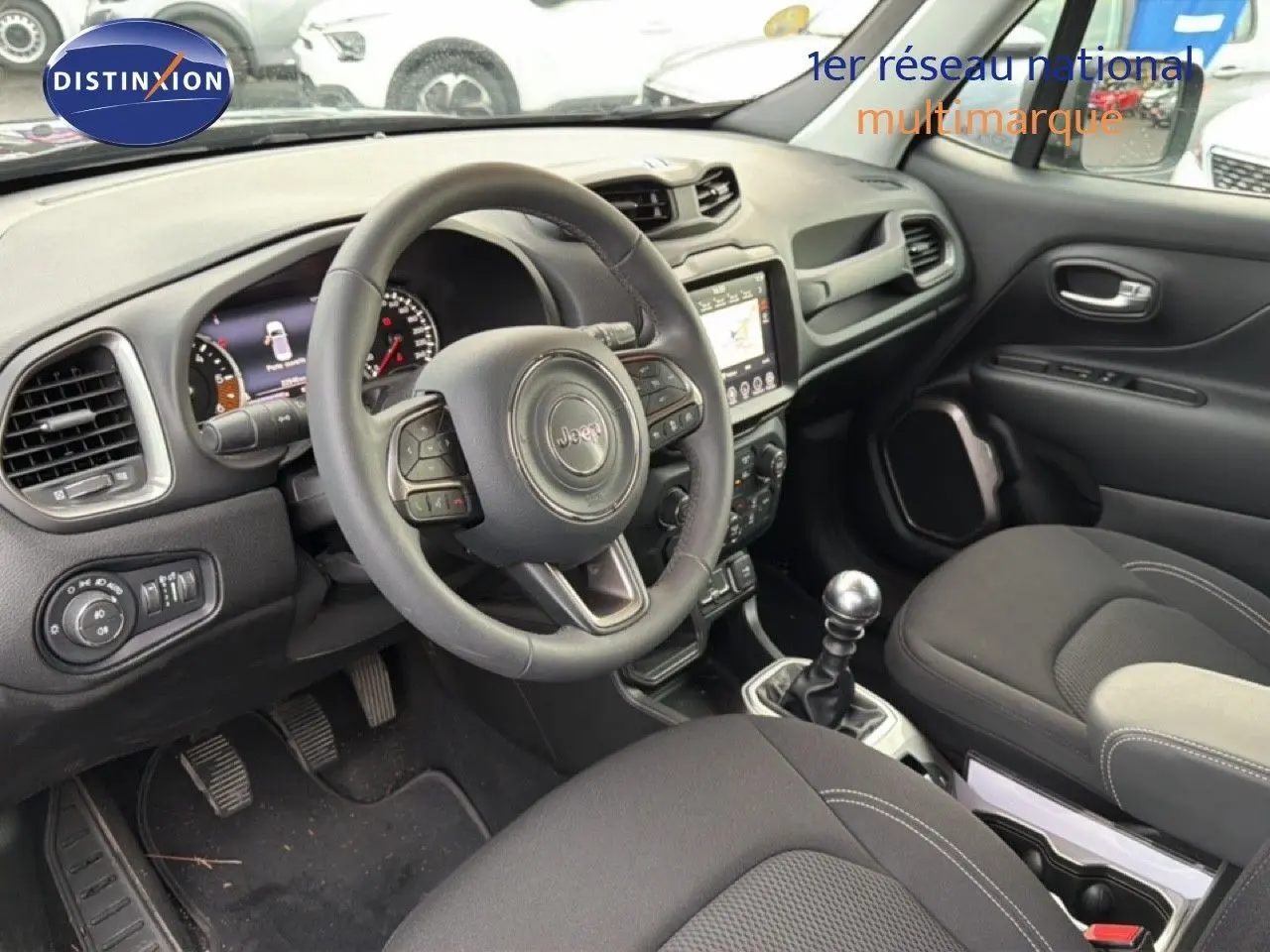 Intérieur noir du Jeep Renegade 2022, vue côté conducteur montrant volant, tableau de bord et levier de vitesse manuel.