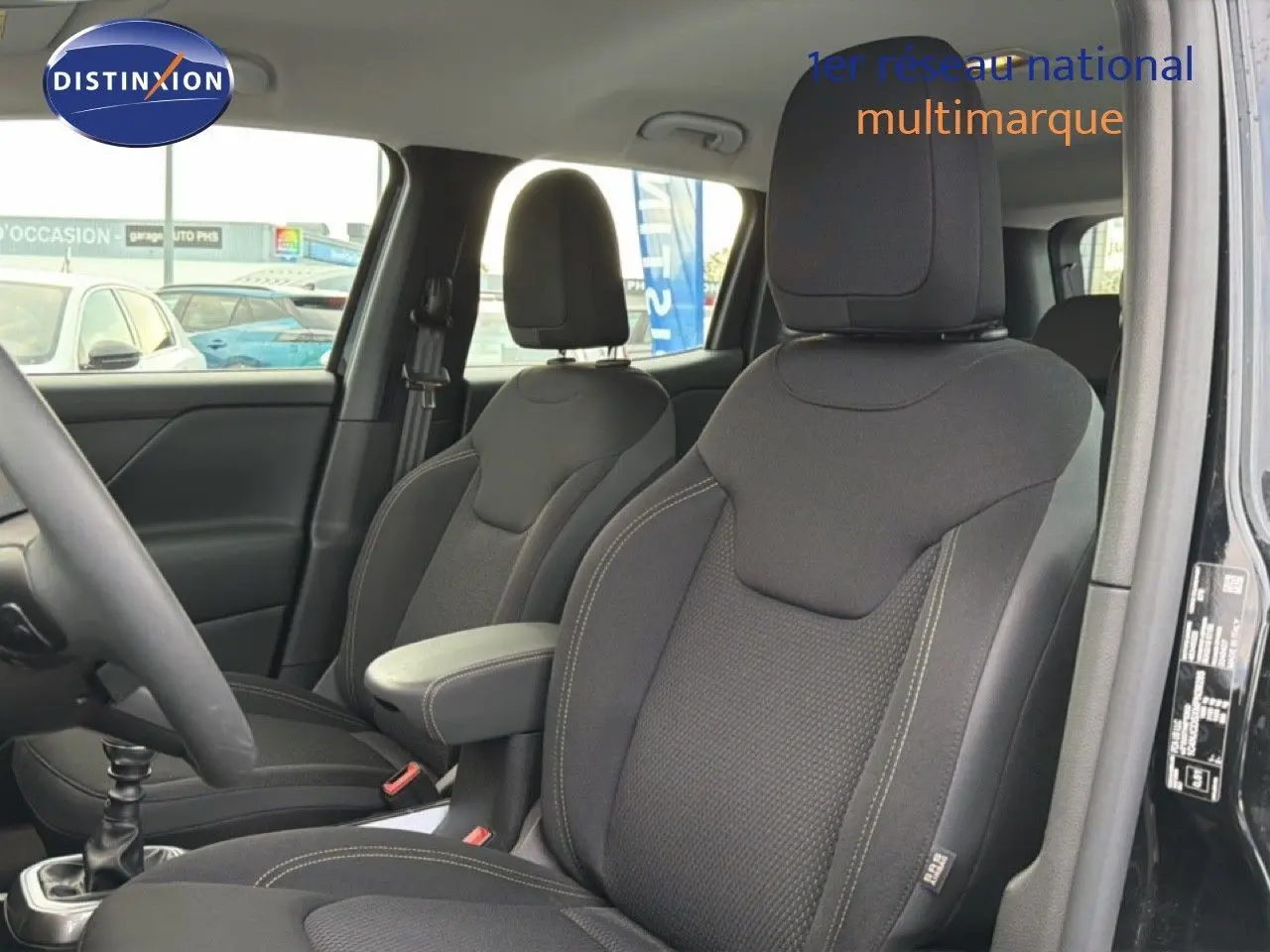 Vue intérieure côté conducteur du Jeep Renegade noir 2022, sièges tissus gris foncé avec accoudoir central.