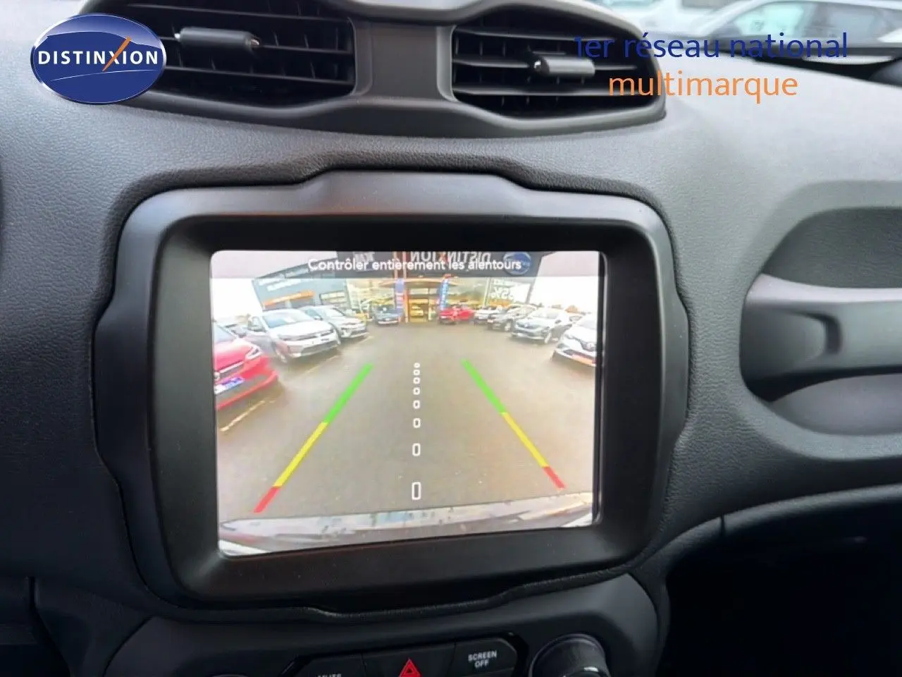 Écran central affichant la caméra de recul d'une Jeep Renegade noire, vue intérieure du tableau de bord.