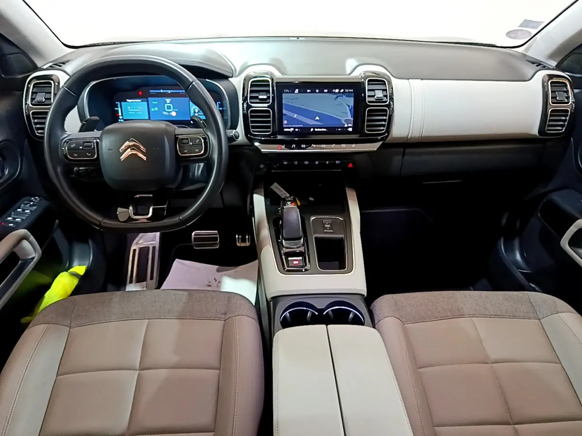 Intérieur du Citroën C5 Aircross Hybrid 225 vue de face, tableau de bord clair avec écran tactile et volant cuir noir.