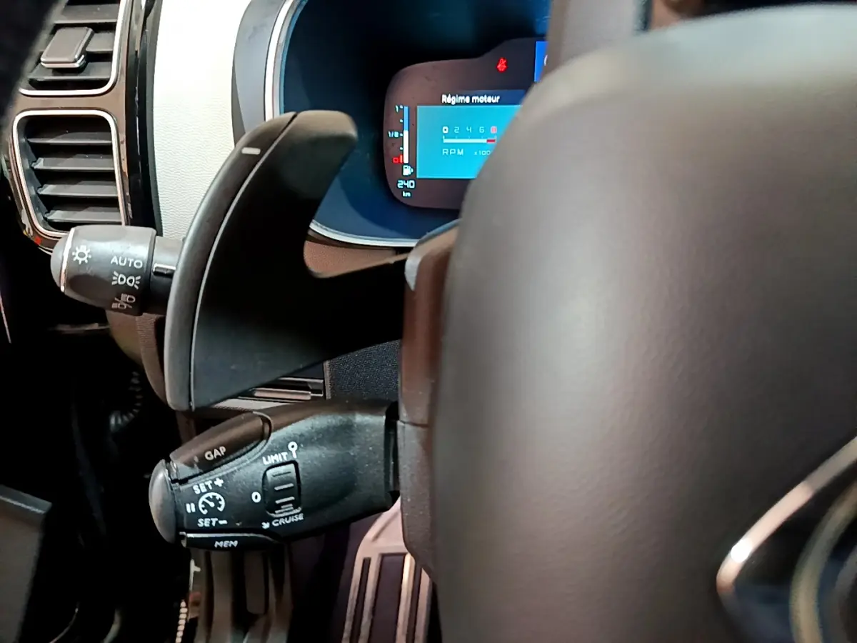 Gros plan sur le volant cuir et les commandes de régulateur de vitesse du tableau de bord numérique du Citroën C5 Aircross Hybrid noir.