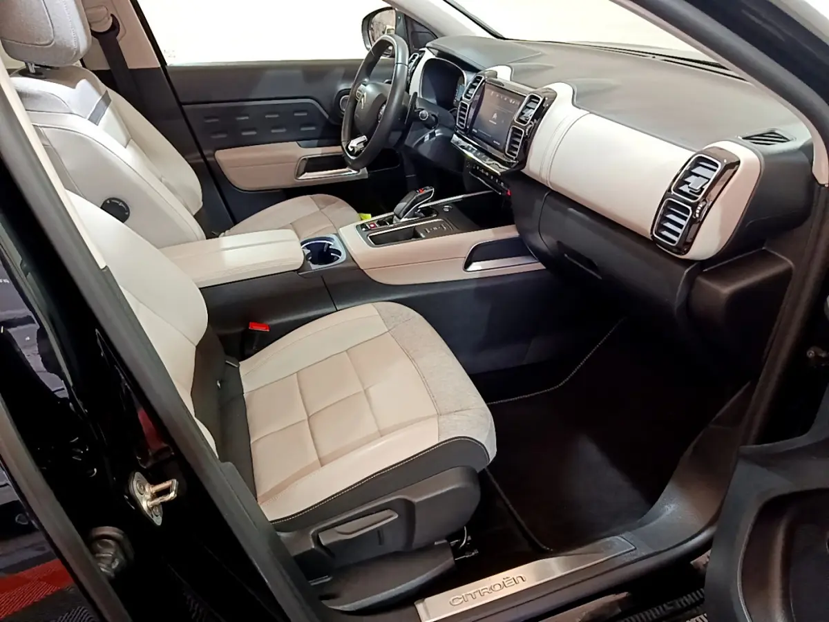 Intérieur avant droit du Citroën C5 Aircross Hybrid noir, sièges clairs et tableau de bord moderne avec écran tactile.