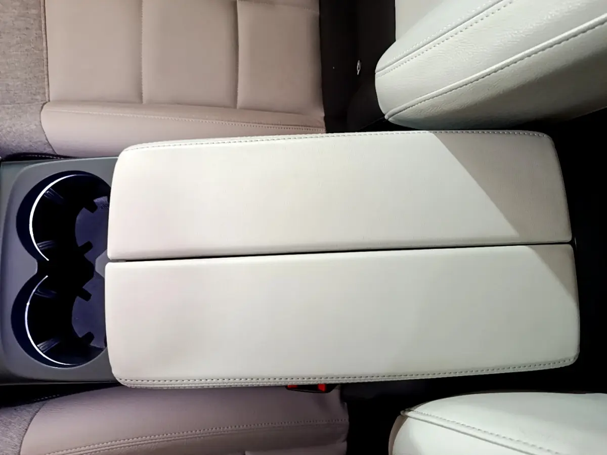 Vue plongeante sur l'accoudoir central beige et porte-gobelets du Citroën C5 Aircross Hybrid 225 ë-EAT8 Shine noir.