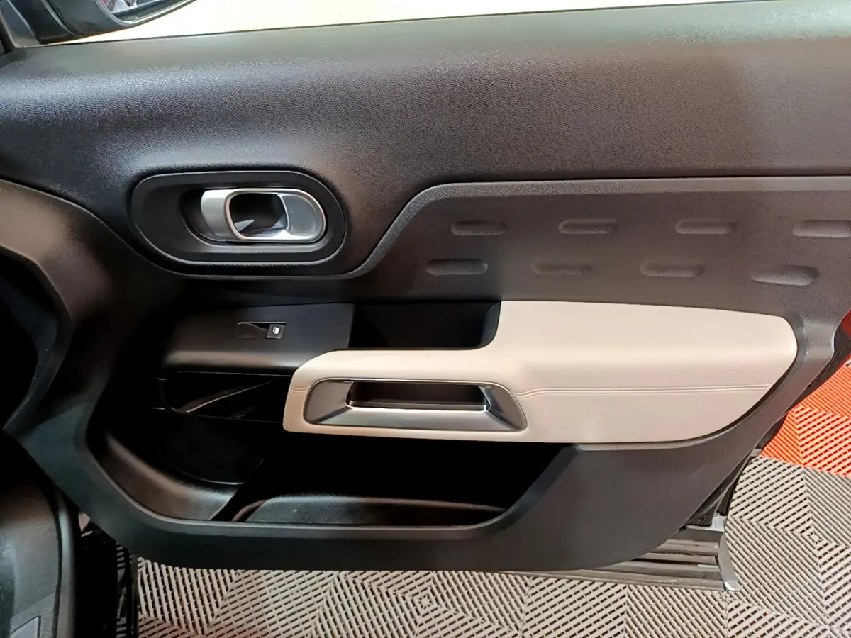 Vue intérieure côté gauche de la porte avant du Citroën C5 Aircross Hybrid 225 ë-EAT8 Shine avec garniture noire et beige.
