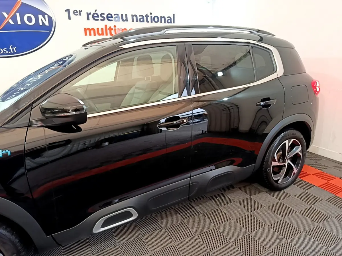 Profil côté gauche du Citroën C5 Aircross Hybrid noir 2021 avec jantes distinctives et protections de bas de caisse grises.