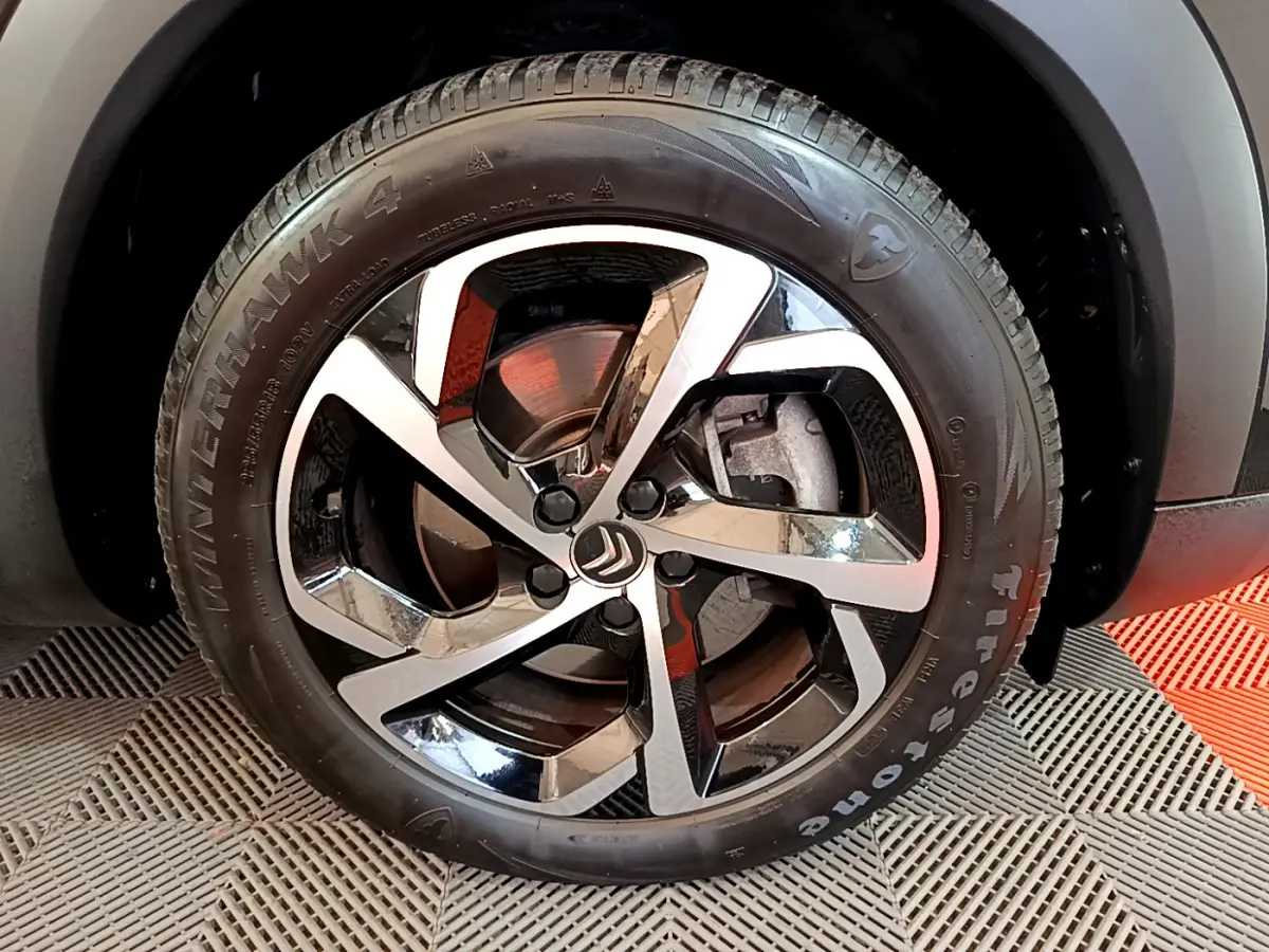 Gros plan sur la roue avant gauche noire du Citroën C5 Aircross Hybrid 225 ë-EAT8 Shine avec jante alliage bicolore.