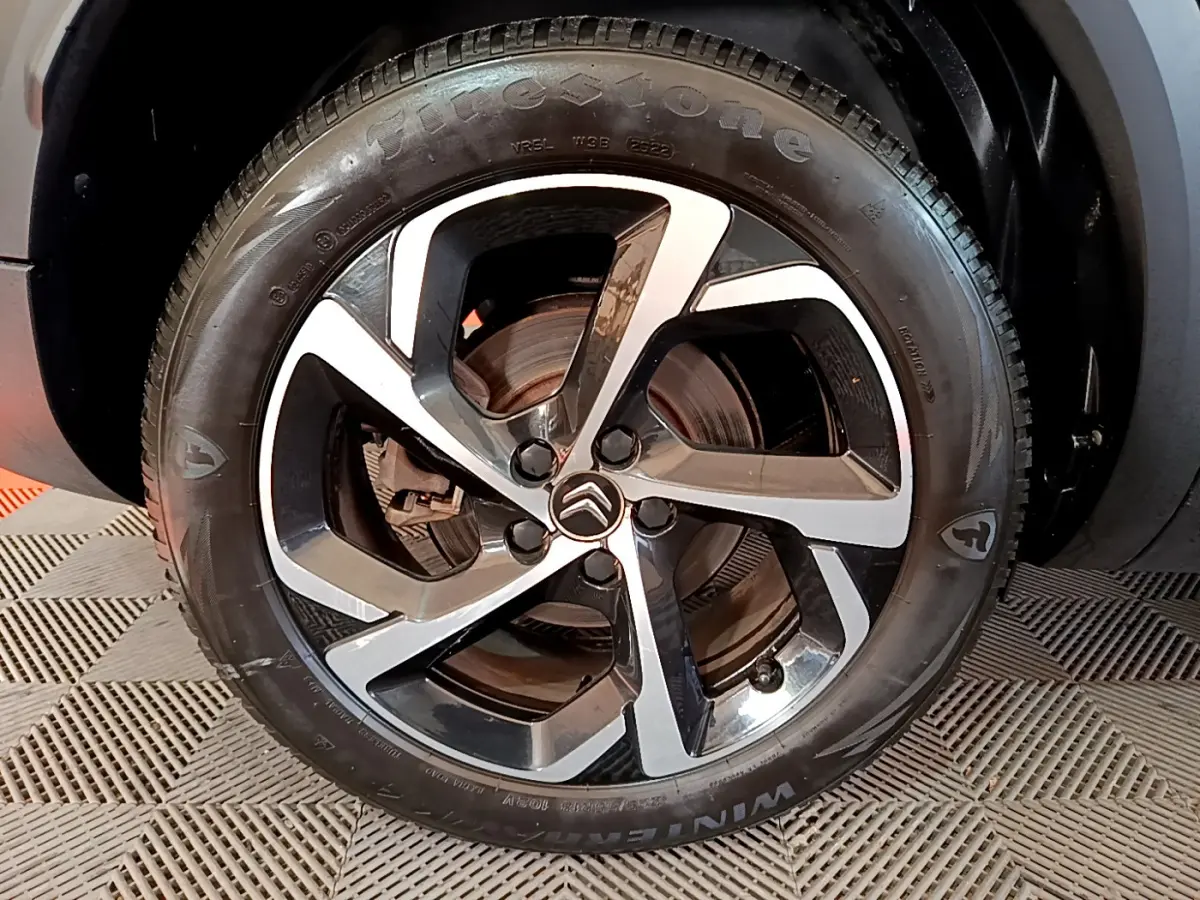 Gros plan sur la jante alliage bicolore et le pneu Firestone du Citroën C5 Aircross Hybrid 225 ë-EAT8 noir, côté arrière.
