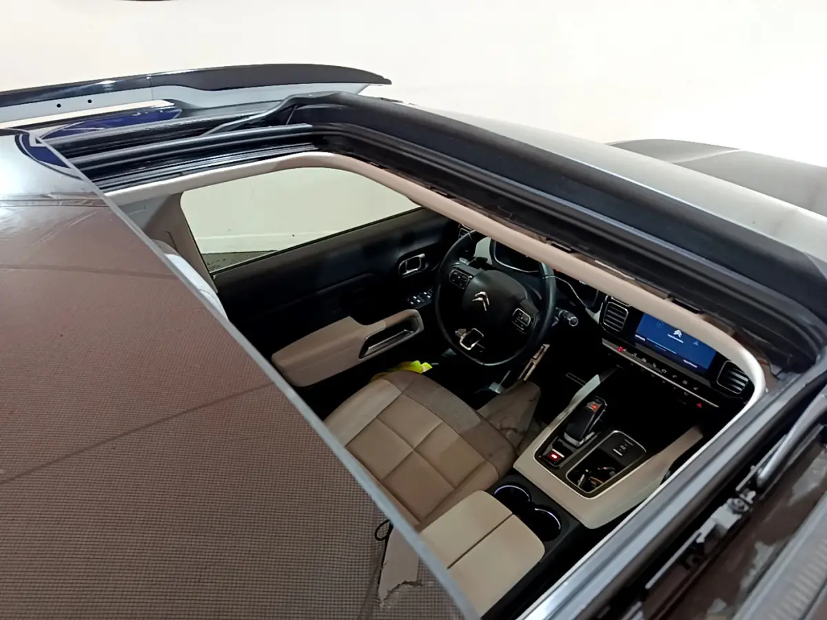 Vue plongeante sur l'intérieur beige et noir du Citroën C5 Aircross Hybrid 225 avec toit ouvrant panoramique.