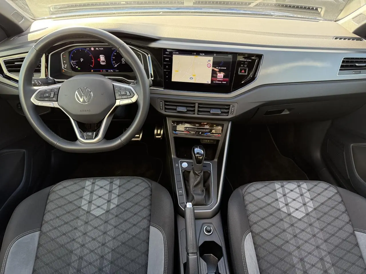 Vue intérieure avant du Volkswagen Taigo 2025 montrant le volant multifonctions, l'écran tactile et la console centrale noire.