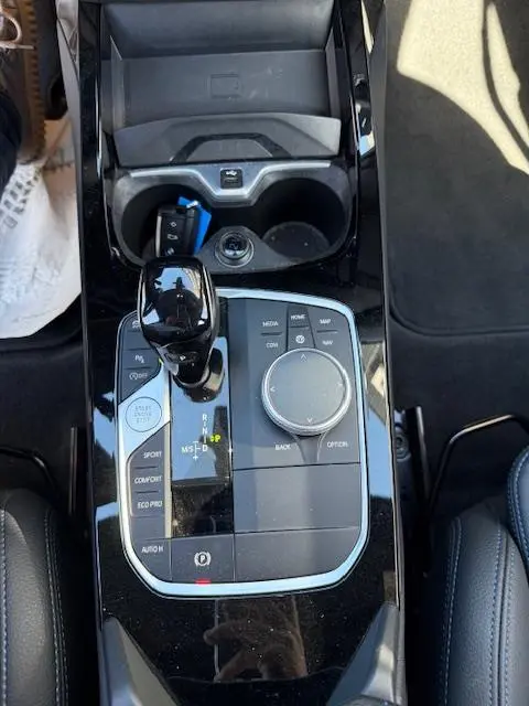 Vue plongeante sur la console centrale noire brillante de la BMW Série 1 118d Edition Sport avec levier de vitesse et molette de sélection.