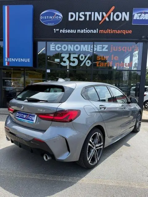 BMW Série 1 118d Edition Sport gris foncé vue 3/4 arrière droite devant un showroom Distinxion.