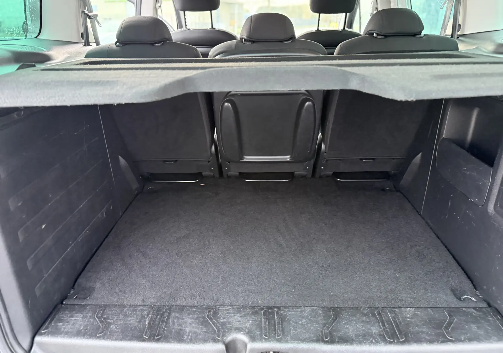 Vue intérieure du coffre spacieux du Peugeot Partner Tepee gris, avec banquette arrière et cache-bagages visibles.