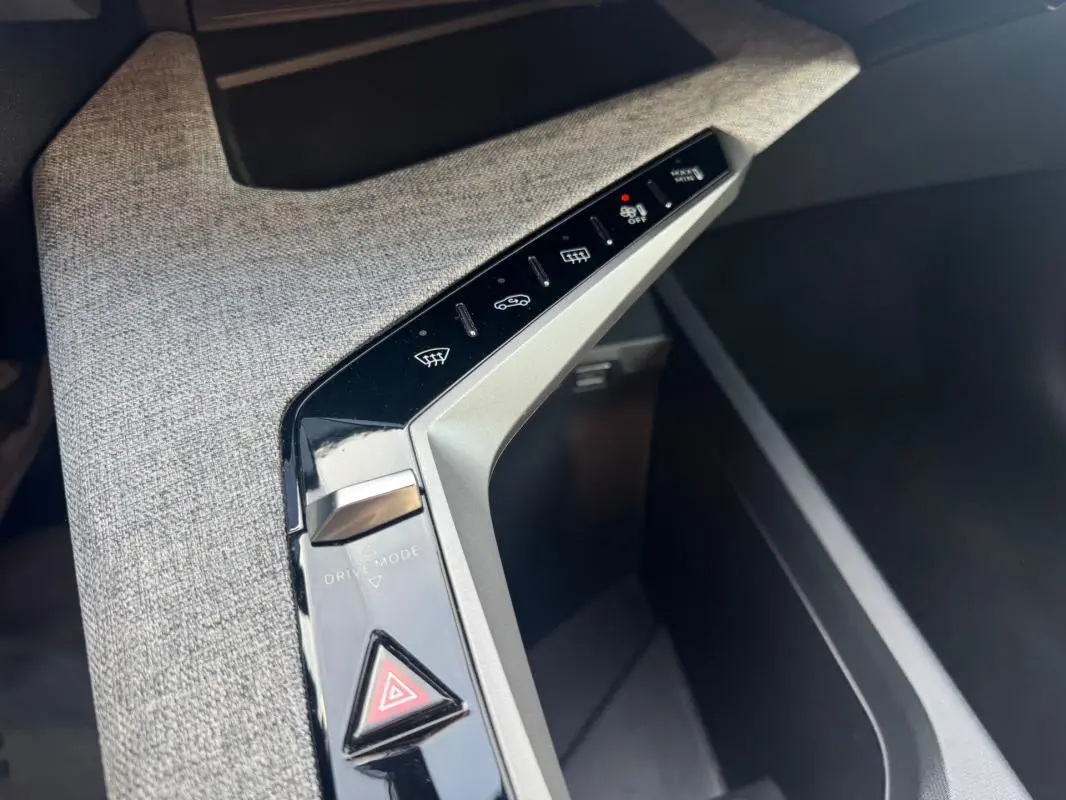 Gros plan sur la console centrale du Peugeot 3008 Hybrid 145 Allure 2025, avec boutons de contrôle et tissu gris.