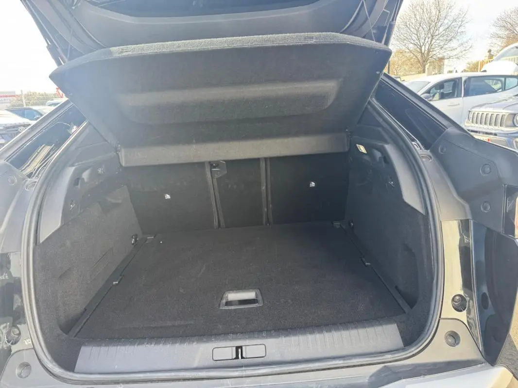 Coffre ouvert vu de l'arrière d'un Peugeot 3008 Hybrid 145 noir, montrant un espace de chargement propre et spacieux.