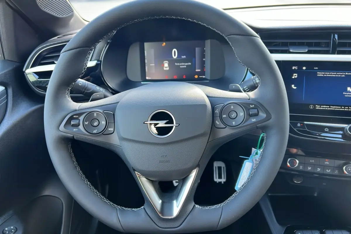 Vue rapprochée du volant cuir multifonctions de l’Opel Corsa Hybrid 110 e-DCT6, avec tableau de bord numérique et écran tactile.