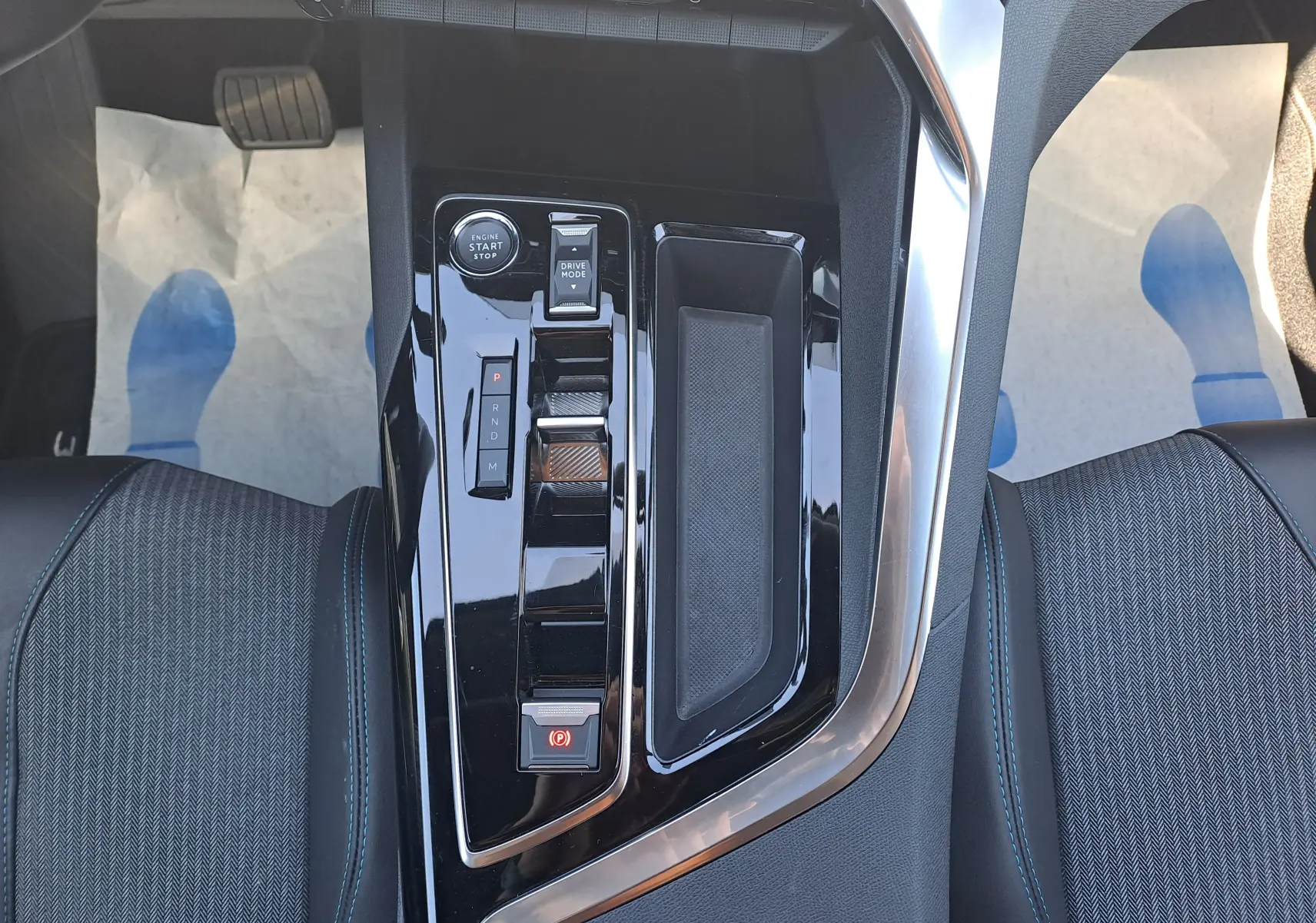 Vue plongeante sur la console centrale noire brillante du Peugeot 3008 2023, avec commandes de boîte auto et rangement.