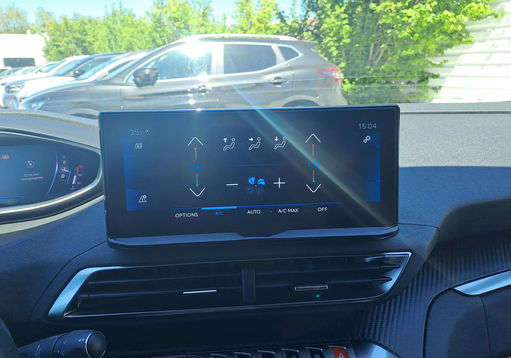 Intérieur du Peugeot 3008 2023 montrant l'écran tactile central de la climatisation, avec tableau de bord noir et extérieur lumineux visible.