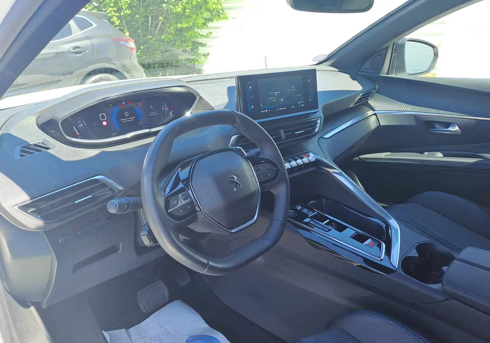 Vue intérieure côté conducteur du Peugeot 3008 2023, tableau de bord numérique et console centrale moderne en noir brillant.