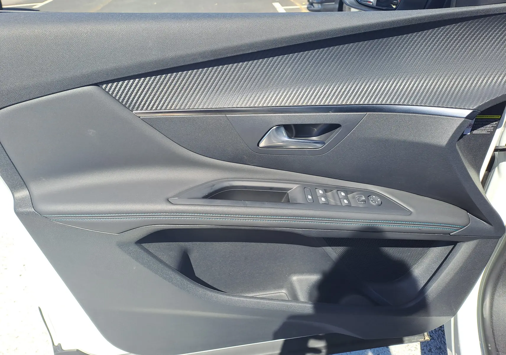 Vue rapprochée de la porte avant gauche du Peugeot 3008 blanc nacré avec garniture noire et surpiqûres bleues.