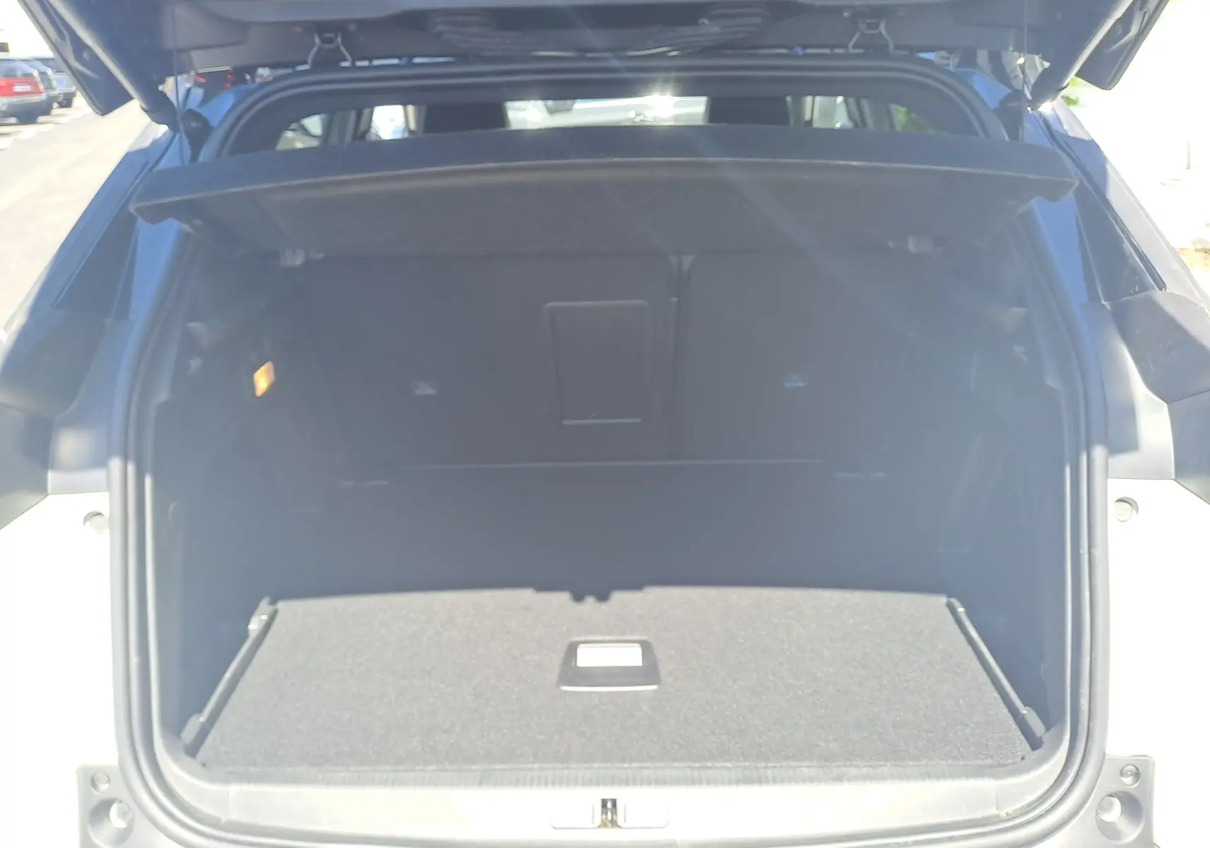 Coffre ouvert vu de l'arrière d'un Peugeot 3008 blanc nacré avec toit noir, montrant un espace de chargement vide.