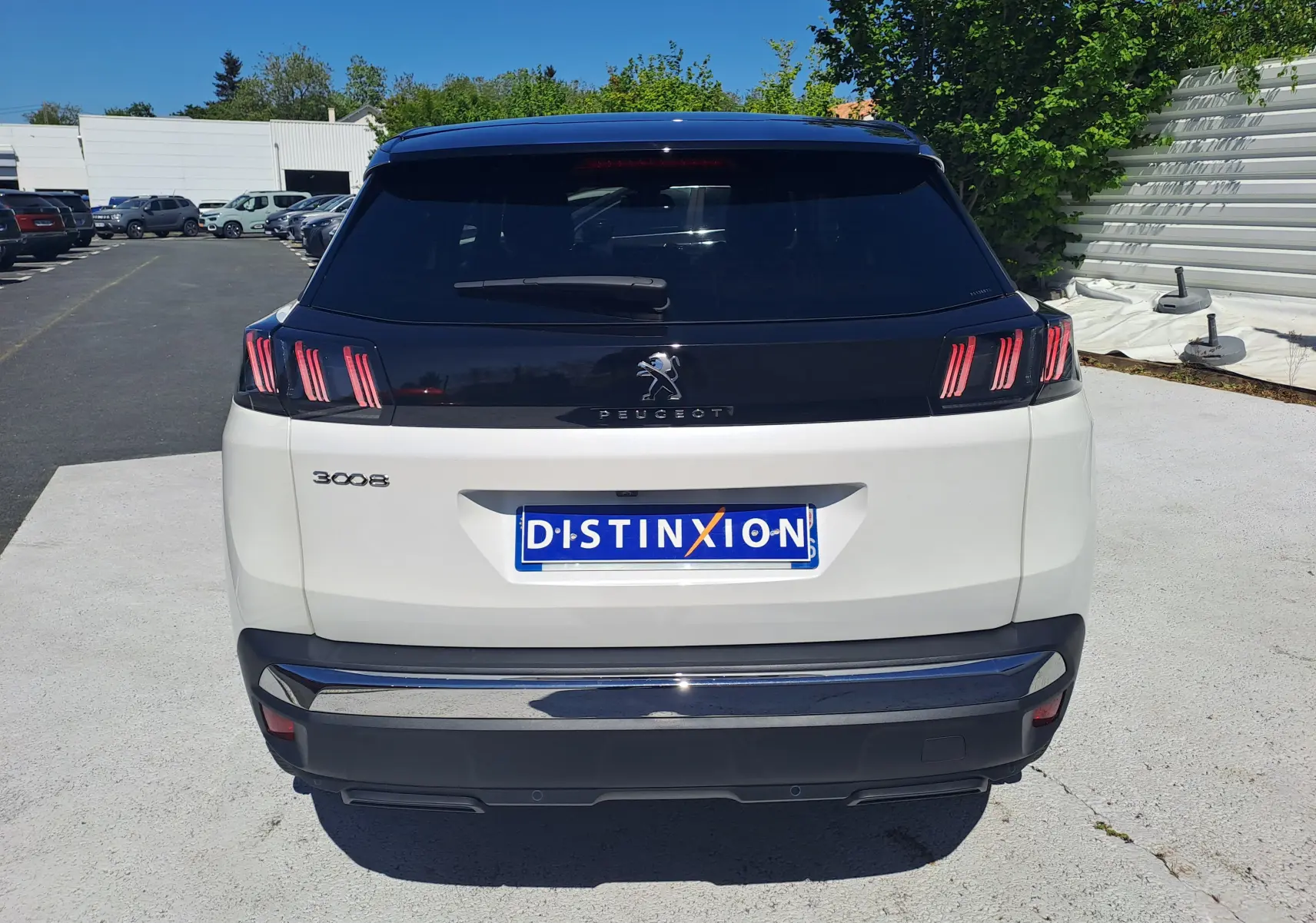 Vue arrière d’un Peugeot 3008 blanc nacré avec toit noir, feux arrière à griffes rouges et plaque Distinxion.