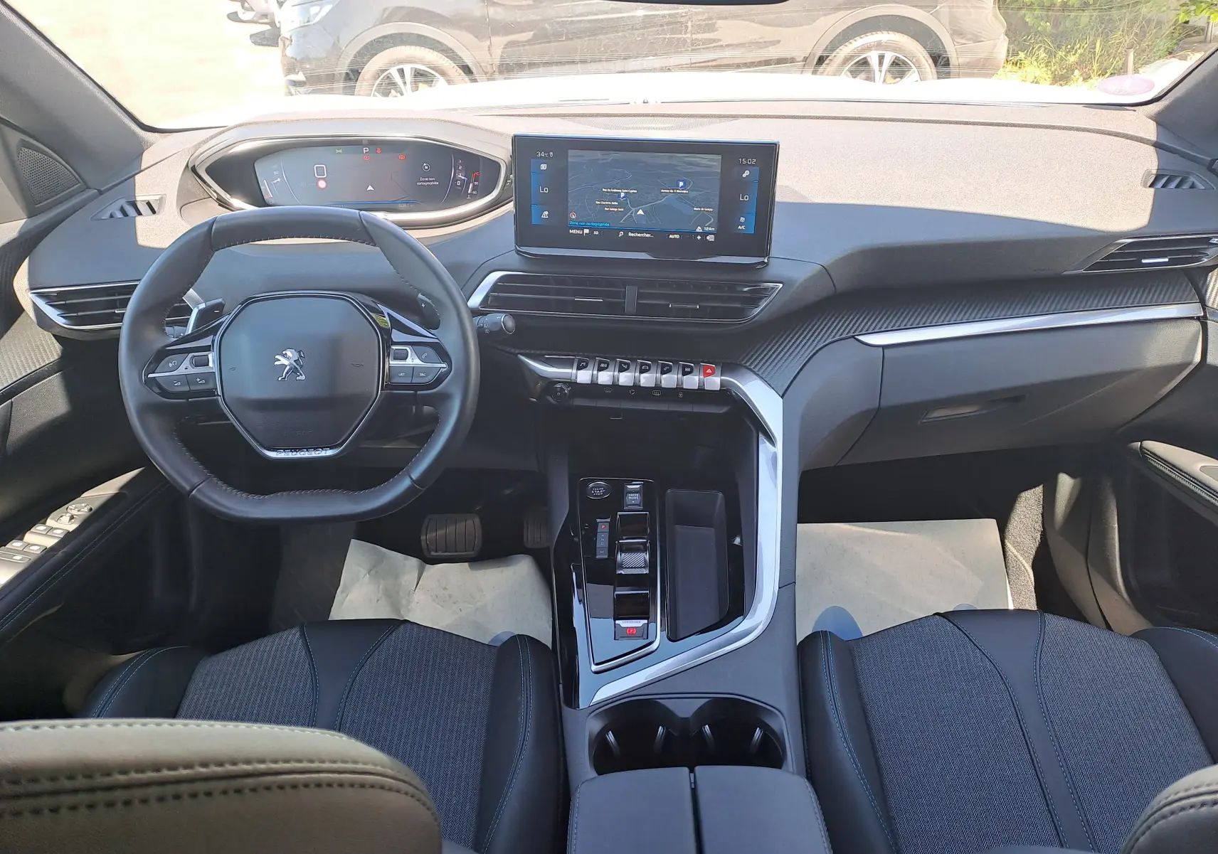 Vue intérieure avant du Peugeot 3008 2023, tableau de bord moderne avec écran central tactile et volant compact noir.