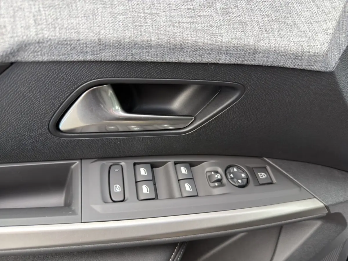 Gros plan sur la poignée intérieure et les commandes de vitres côté conducteur d’un Peugeot 3008 noir, finition Allure.