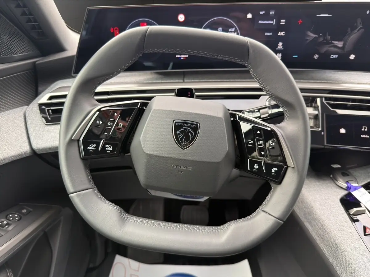 Vue rapprochée du volant cuir gris du Peugeot 3008 2026 avec commandes multifonctions et tableau de bord numérique.