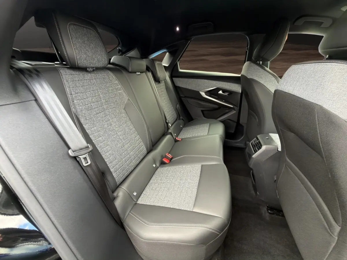 Vue intérieure arrière côté droit du Peugeot 3008 2026 hybride noir, sièges tissu et cuir gris avec ceintures de sécurité.