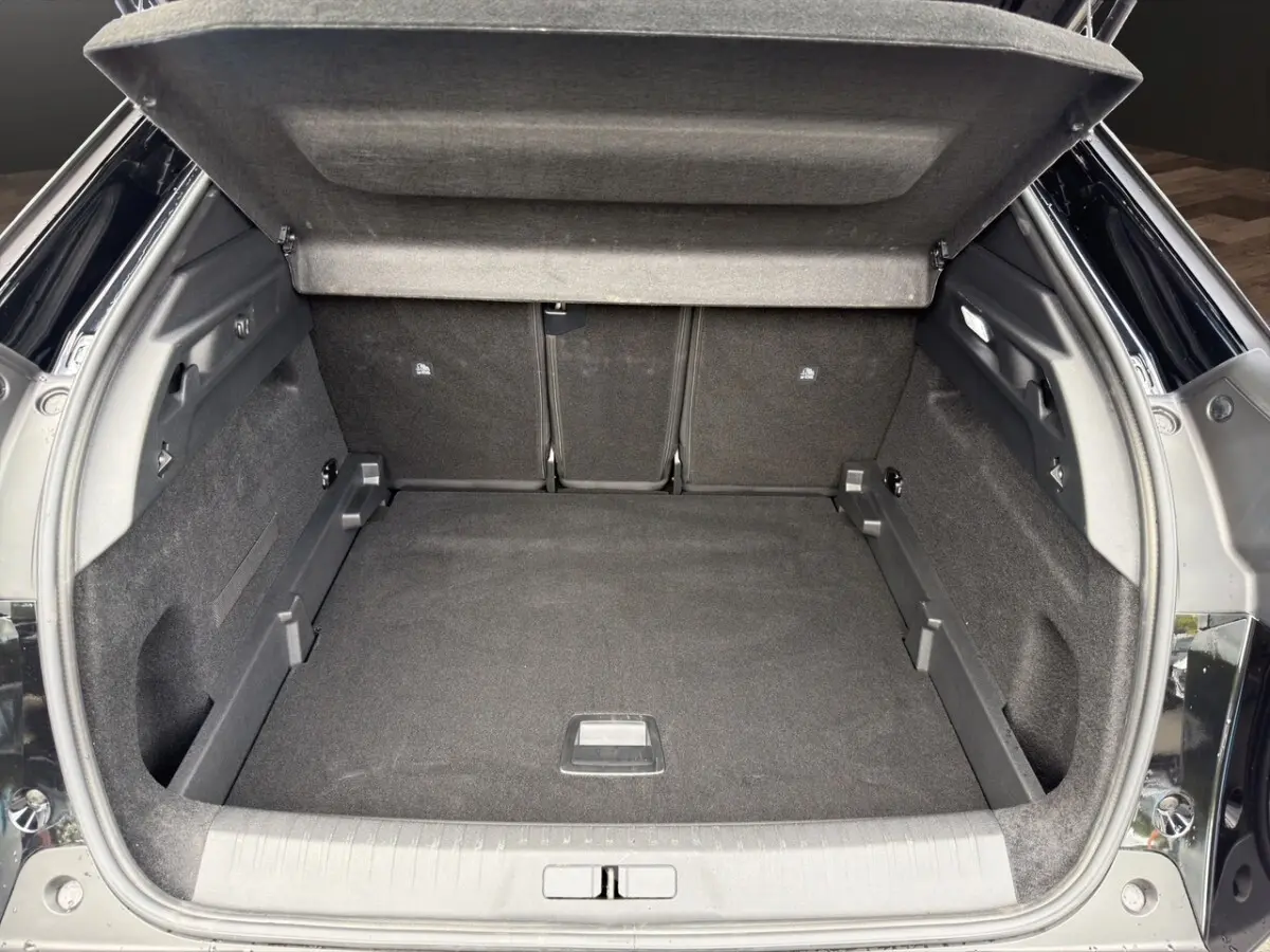 Coffre ouvert noir du Peugeot 3008 1.2 Hybrid 145 vue arrière, montrant l'espace de chargement et la tablette cache-bagages.