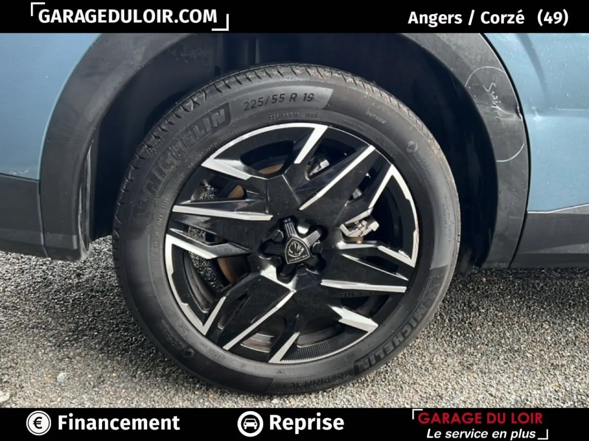 Gros plan sur la roue avant droite d’un Peugeot 5008 bleu 2024 avec jante alliage noire et argentée.