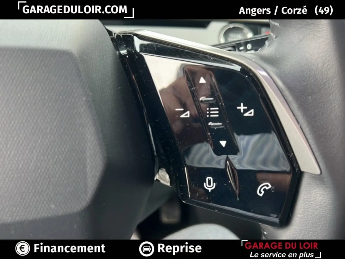 Gros plan sur les commandes au volant noir brillant du Peugeot 5008 bleu 1.2 Hybrid 136 Allure, côté gauche.