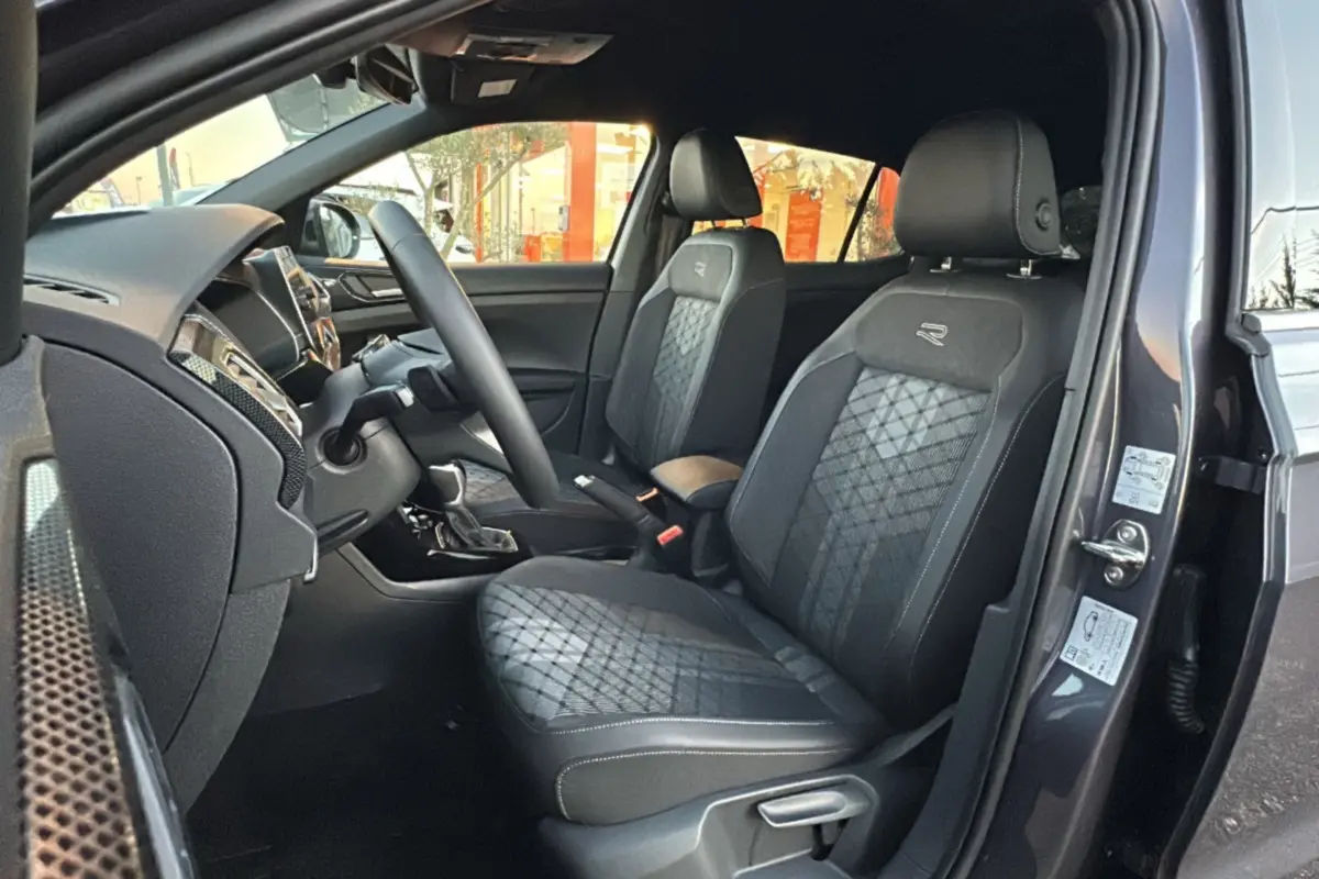 Intérieur avant du Volkswagen T-Cross gris cendré, vue côté gauche, sièges tissu avec logo R et volant cuir multifonctions.