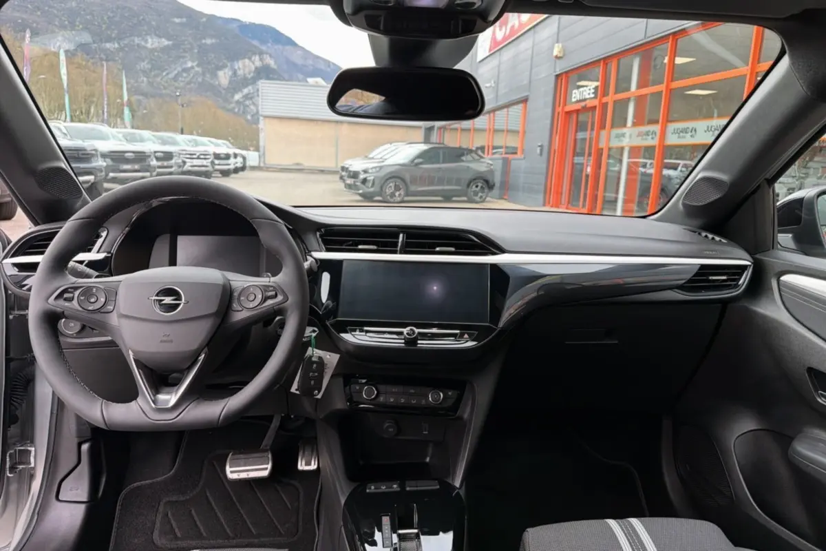 Intérieur de l’Opel Corsa Hybrid 110 e-DCT6 gris kristall, vue du poste de conduite avec volant multifonctions et écran tactile central.
