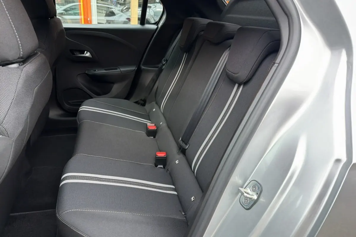Vue intérieure arrière côté droit de l’Opel Corsa gris kristall, banquette tissu noire avec bandes grises et ceintures rouges.