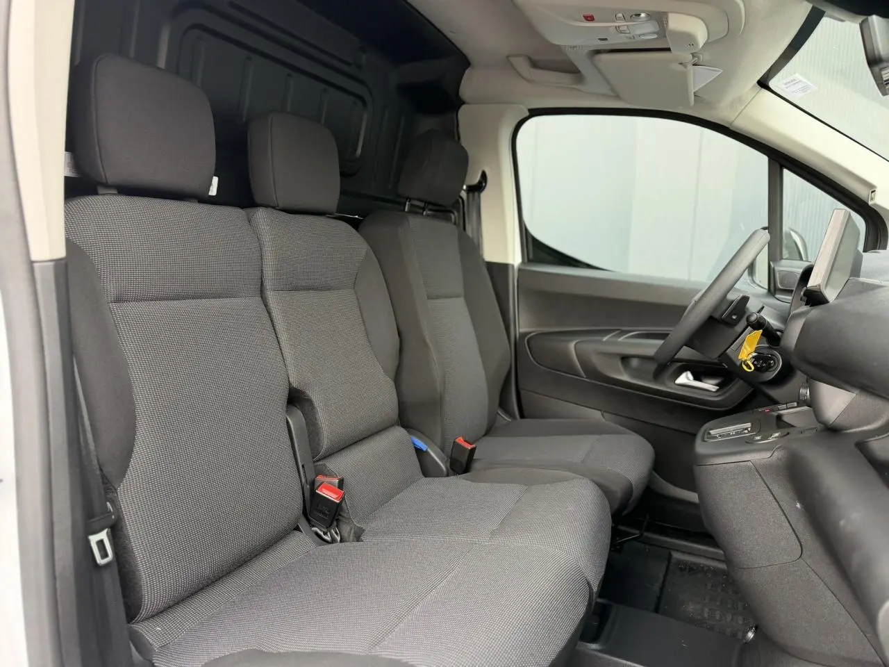 Vue intérieure côté conducteur du Citroën Berlingo Van XL 2026 avec sièges tissu gris et plancher bois visible à l'arrière.