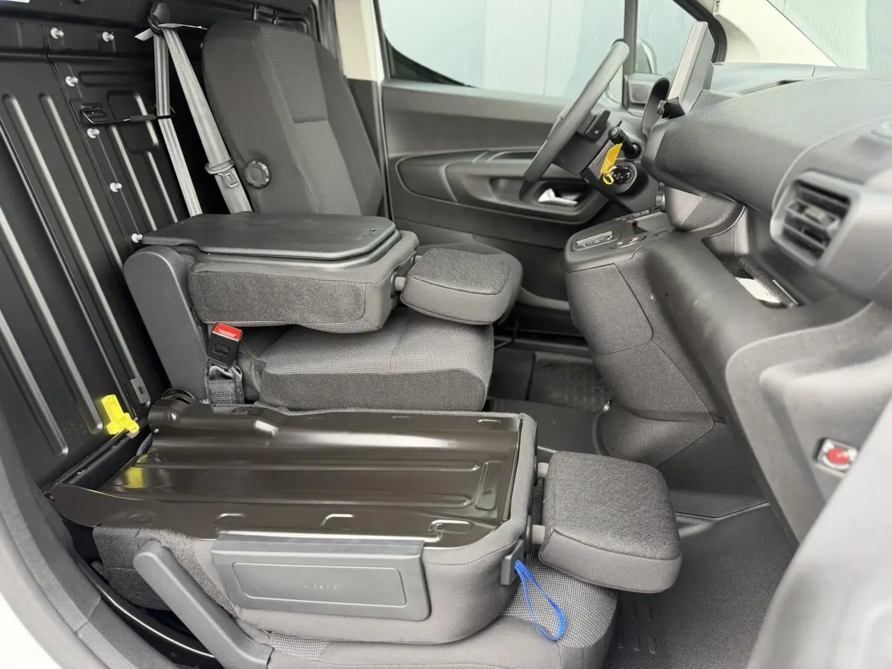 Vue intérieure côté conducteur du Citroën Berlingo Van XL 2026, sièges tissu gris avec plancher bois antidérapant.