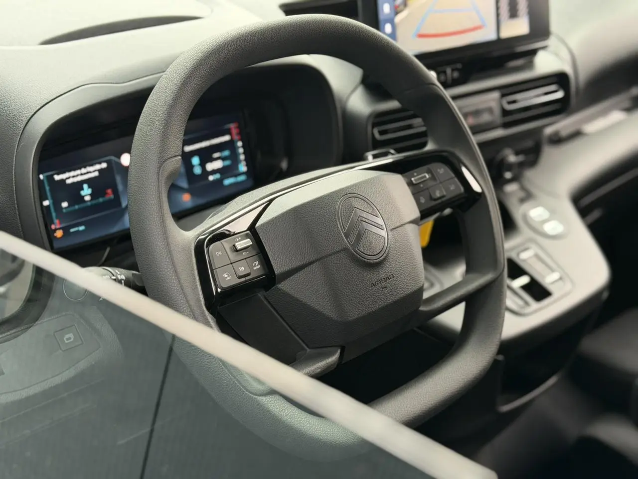 Vue intérieure centrée sur le volant multifonctions noir du Citroën Berlingo avec tableau de bord numérique et écran tactile.