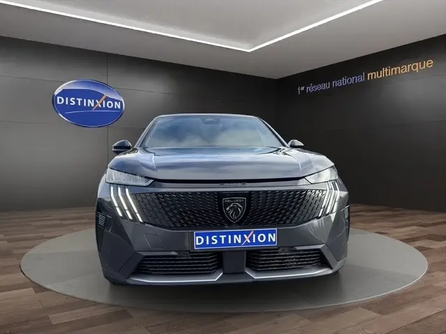 Vue frontale d’un Peugeot 3008 gris foncé avec calandre noire et feux LED verticaux distinctifs en showroom.