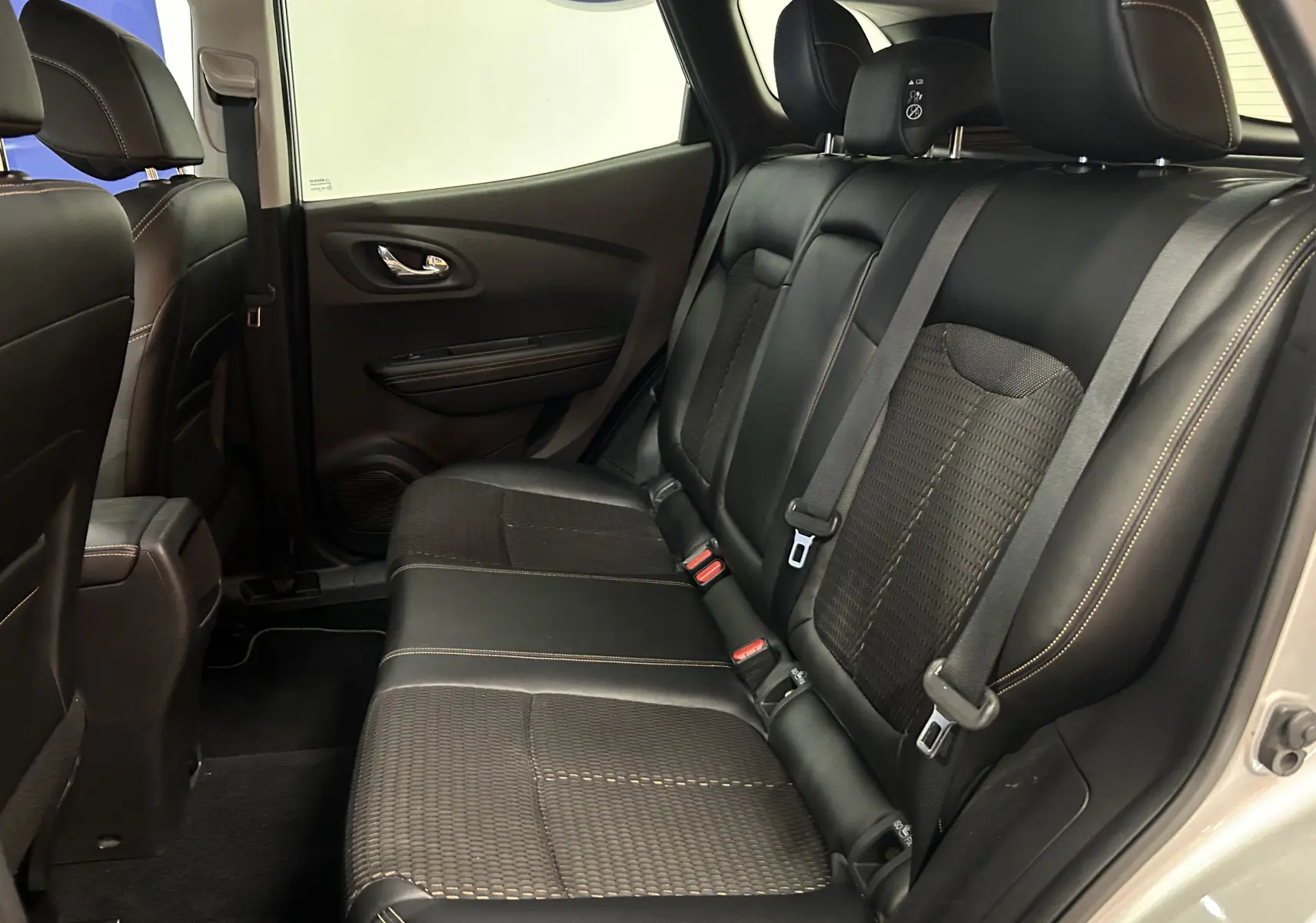Vue intérieure arrière droite du Renault Kadjar gris 2015, sièges en tissu et cuir noir avec surpiqûres contrastées.
