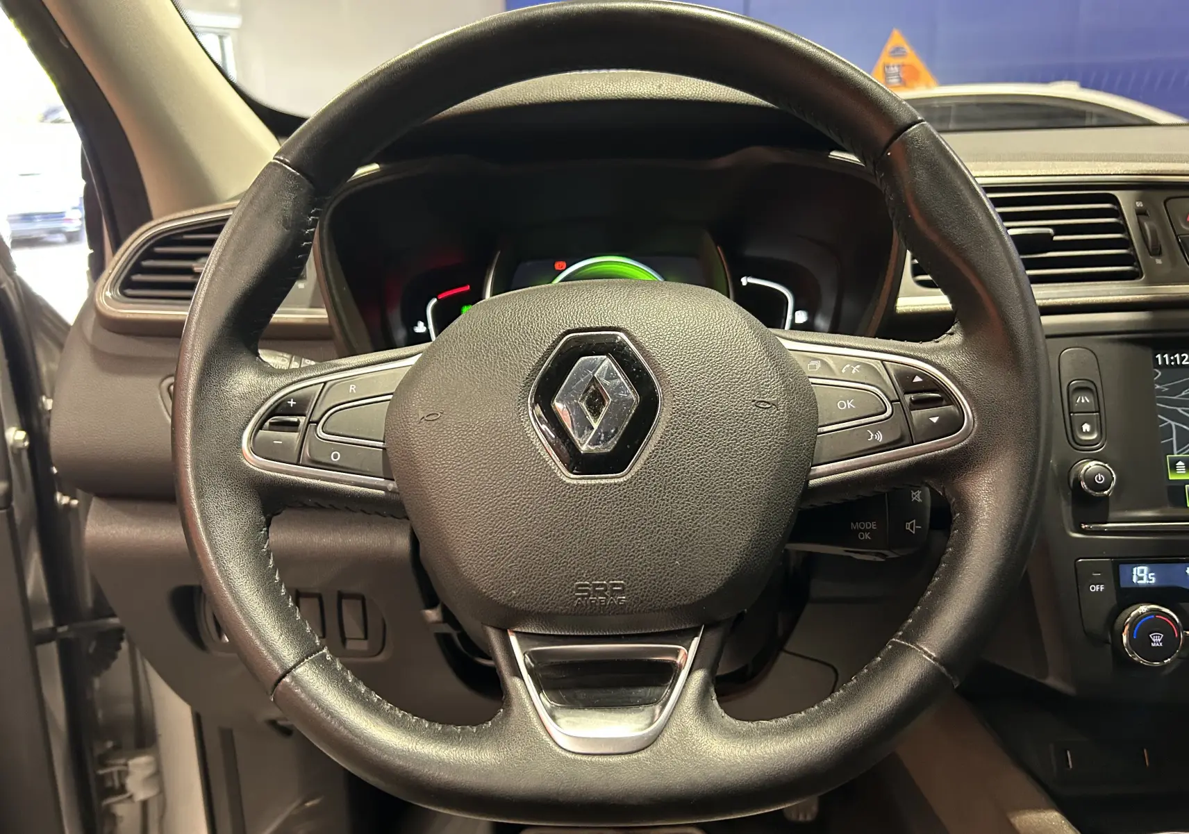 Vue rapprochée du volant cuir noir du Renault Kadjar gris 2015 avec commandes intégrées et tableau de bord digital.