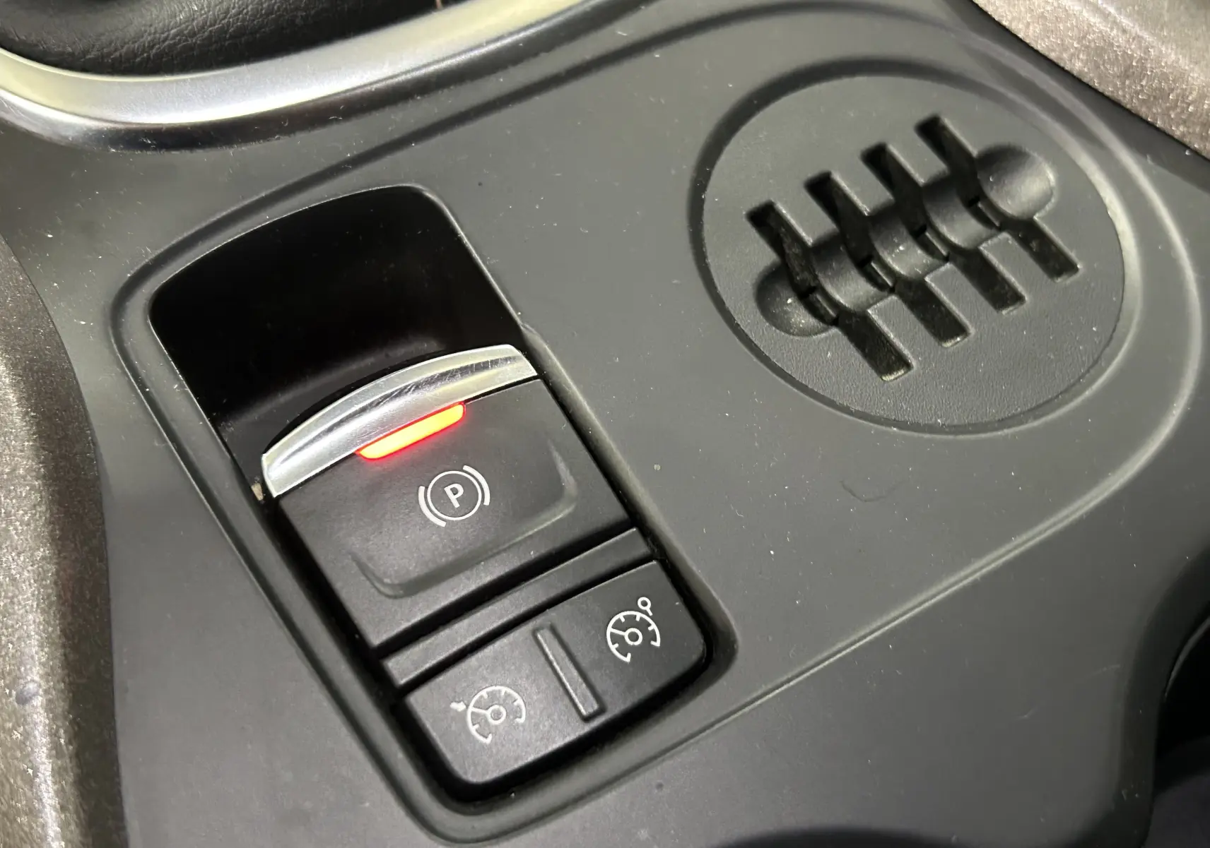 Gros plan sur les commandes de frein à main électronique et régulateur de vitesse du Renault Kadjar gris, version 2015.