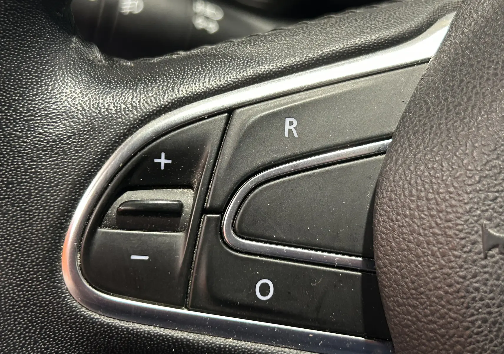 Gros plan sur les commandes de régulateur de vitesse au volant en cuir noir du Renault Kadjar gris de 2015.